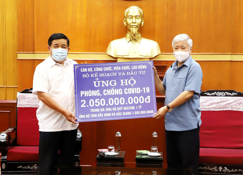 Chủ tịch Ủy ban Trung ương Mặt trận Tổ quốc Việt Nam Đỗ Văn Chiến tiếp nhận ủng hộ Quỹ vaccine phòng COVID-19 từ Bộ trưởng Bộ Kế hoạch và Đầu tư Nguyễn Chí Dũng. (Ảnh: Minh Đức/TTXVN)