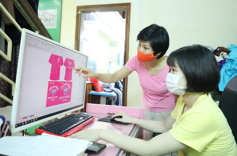 Chị Nghiêm Thị Thu Hường, Chủ nhiệm Cơ sở May Công nghiệp của người khuyết tật tỉnh Lạng Sơn hướng dẫn học viên thiết kế quần áo trên máy tính. (Ảnh: Anh Tuấn/ TTXVN)