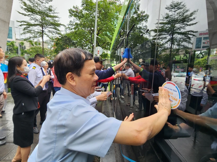 Các đại biểu dán các khẩu hiệu tuyên truyền trên xe buýt điện nhằm ủng hộ Tuần lễ An toàn giao thông đường bộ toàn cầu lần thứ 7. (Ảnh: Việt Hùng/Vietnam+)