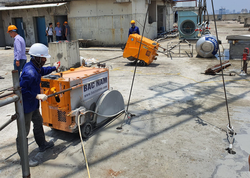 Máy cắt bê tông dây kim cương thực hiện cắt sàn tầng 18 tòa nhà 8B Lê Trực. (Ảnh: Mạnh Khánh/TTXVN)