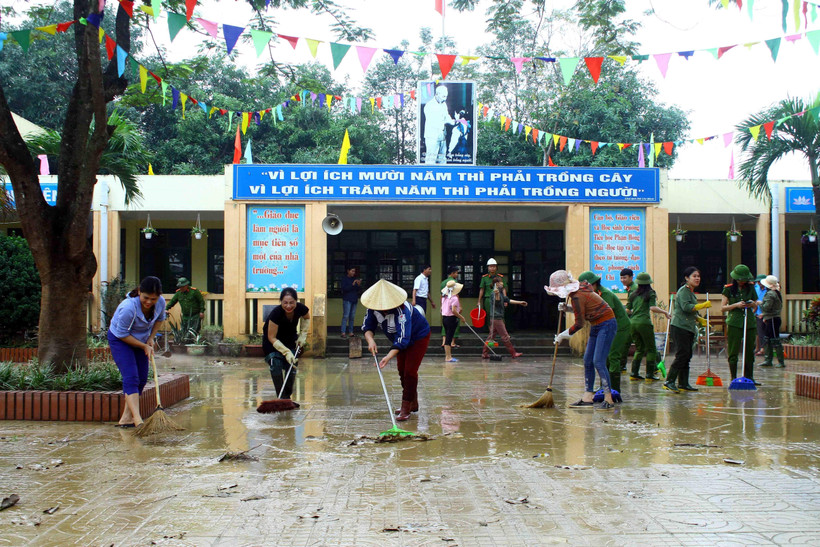 Lực Công an huyện Hưng Nguyên (Nghệ An) cùng giáo viên Trường Tiểu học Phạm Hồng Thái (xã Châu Nhân, huyện Hưng Nguyên) dọn vệ sinh môi trường sau mưa lũ để học sinh sớm đi học trở lại. (Ảnh: Tá Chuyên/TTXVN)