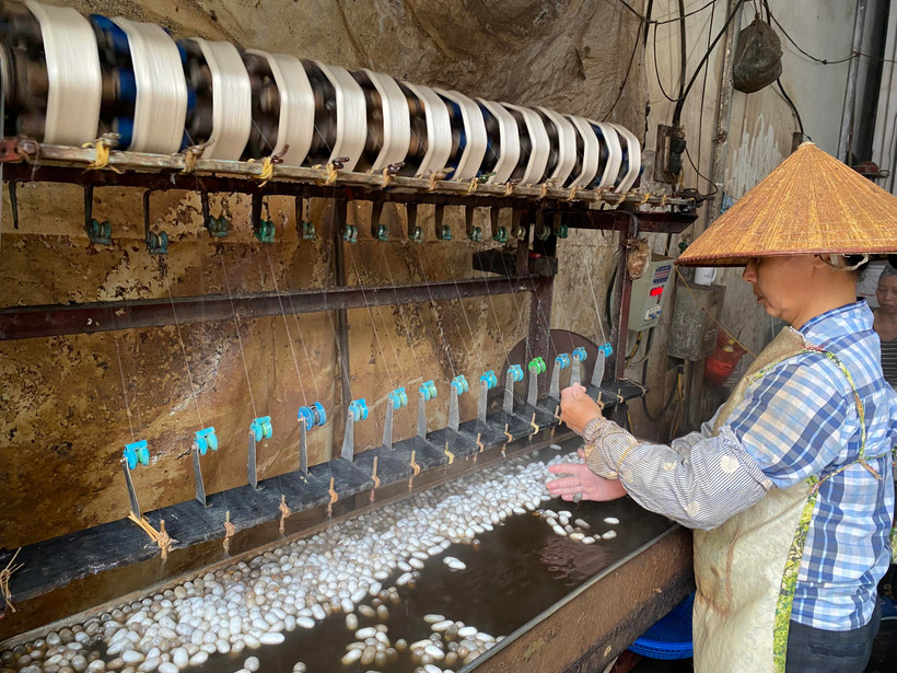 Đôi tay của người thợ ươm tơ bợt trắng vì liên tục đảo kén ,đánh mối và tỉa sợi tơ. (Ảnh: Bích Hằng/Vietnam+)