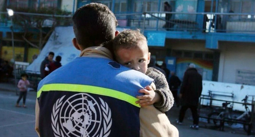 Thành viên Cơ quan cứu trợ và việc làm của LHQ dành cho người tị nạn Palestine (UNRWA) bên một em nhỏ Palestine ở Dải Gaza. (Ảnh: UN News/TTXVN)