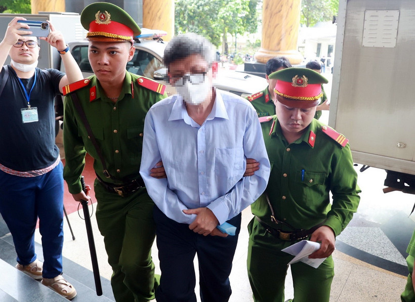 Lực lượng chức năng dẫn giải bị cáo Nguyễn Thanh Long (cựu Bộ trưởng Bộ Y tế) đến phiên tòa. (Ảnh: Phạm Kiên/TTXVN)