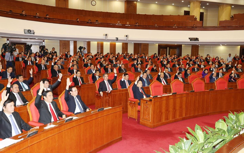 Các đồng chí lãnh đạo Đảng, Nhà nước và các đại biểu biểu quyết thông qua Nghị quyết Hội nghị Trung ương lần thứ mười một. (Ảnh: Trí Dũng/TTXVN)