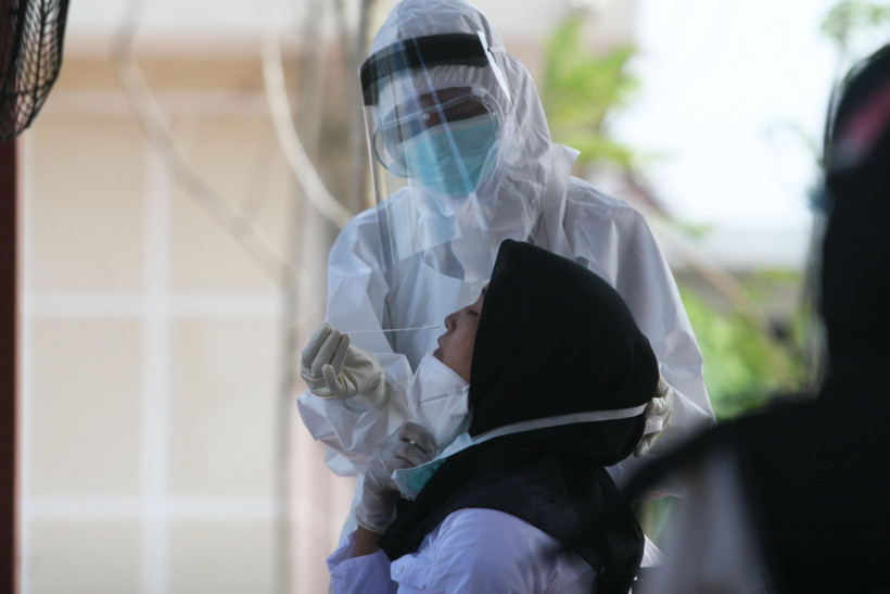 Nhân viên y tế lấy mẫu dịch xét nghiệm COVID-19 cho người dân tại Surabaya, Indonesia. (Ảnh: THX/TTXVN)