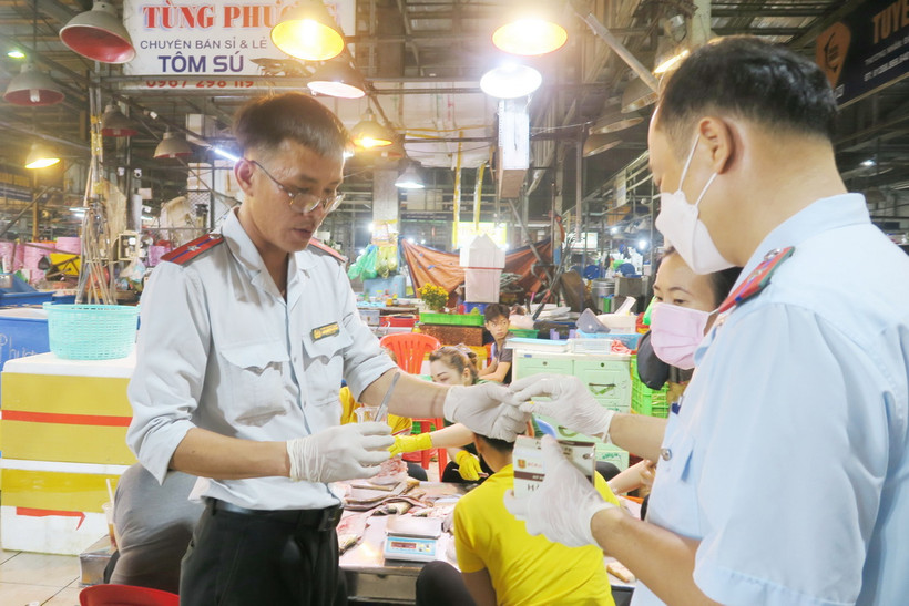 Nhân viên Sở An toàn thực phẩm Thành phố Hồ Chí Minh lấy mẫu kiểm nghiệm nhanh tại chợ đầu mối Bình Điền. (Ảnh: Đinh Hằng/TTXVN)