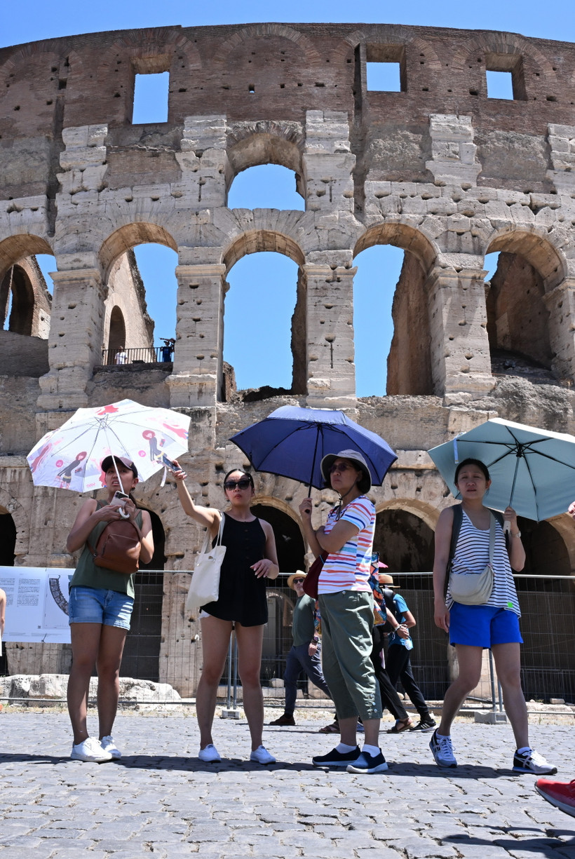 Khách du lịch che ô tránh nắng nóng khi tham quan Đấu trường La Mã ở Rome, Italy ngày 12/7/2024. (Ảnh: THX/TTXVN)