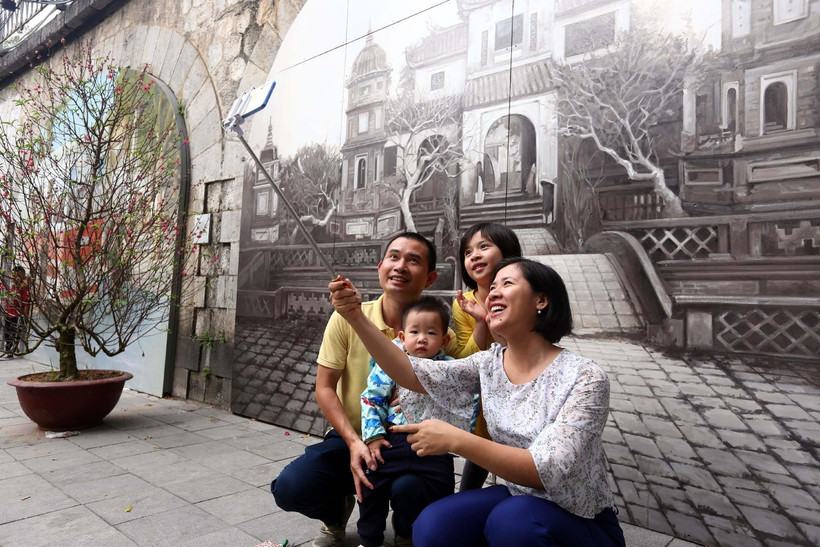 Người dân thủ đô chụp ảnh lưu niệm tại phố Bích họa Phùng Hưng. (Ảnh: Danh Lam/TTXVN)