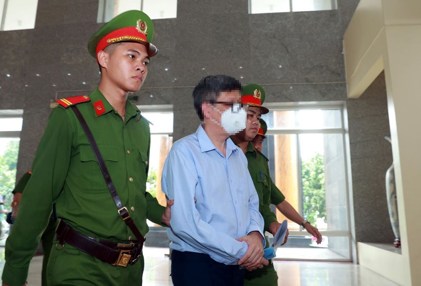 Lực lượng chức năng dẫn giải bị cáo Nguyễn Thanh Long (cựu Bộ trưởng Bộ Y tế) đến phiên tòa. (Ảnh: Phạm Kiên/TTXVN)