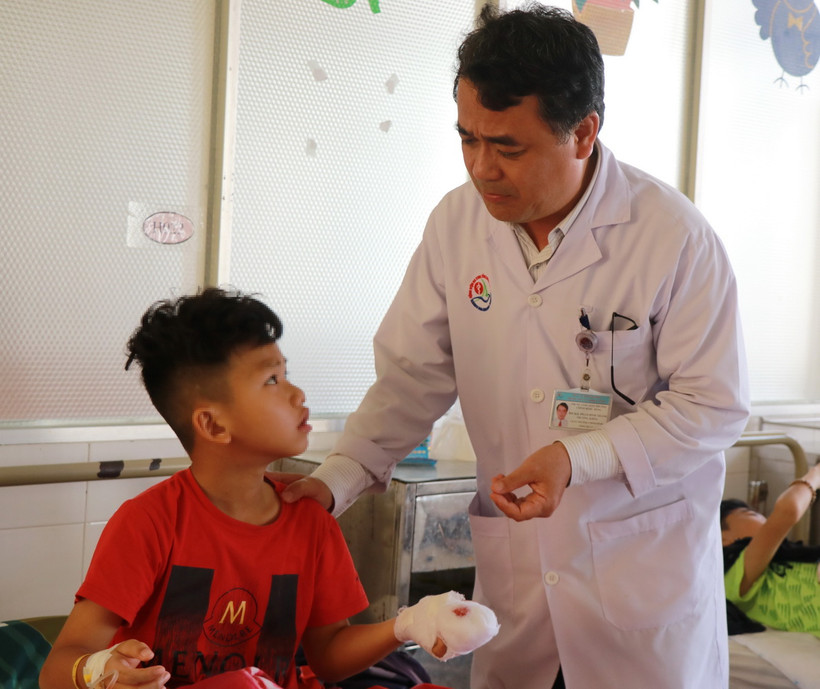 Bác sỹ Chuyên khoa II Phạm Đình Thành, Phó Giám đốc Trung tâm Chấn thương chỉnh hình-Bỏng, Bệnh viện Đa khoa tỉnh Khánh Hòa, thăm bệnh nhân bị chấn thương các ngón tay do pháo hoa. (Ảnh: Phan Sáu/TTXVN)