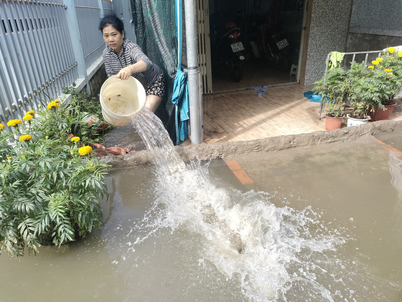 Bà Thái Thị Mãi, ấp 7, xã Châu Bình, huyện Giồng Trôm liên tục tát nước ra ngoài để tránh gây ngập nước khu vực nhà ở. (Ảnh: Huỳnh Phúc Hậu/TTXVN)
