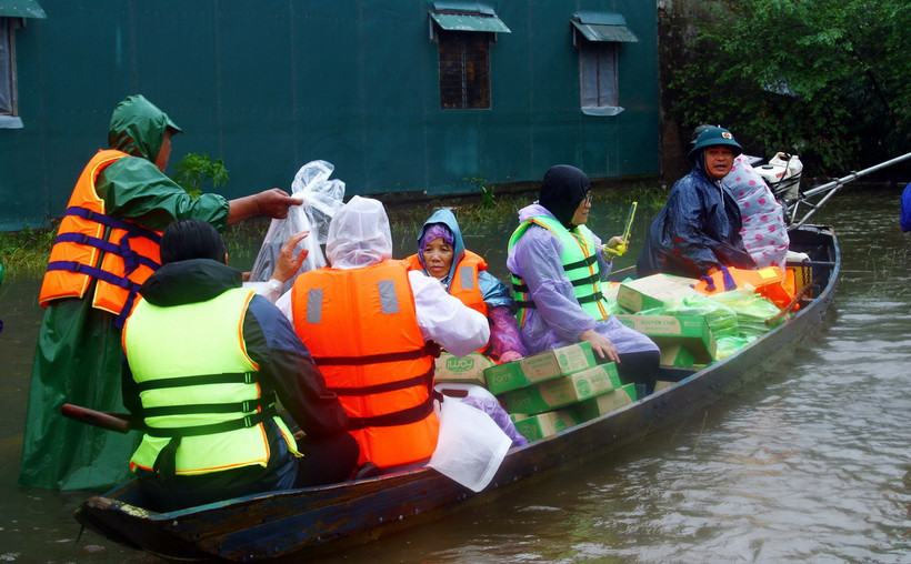 Dùng thuyền vận chuyển nhu yếu phẩm, nước sạch đến người dân các vùng thấp trũng còn bị ngập nước của huyện Lệ Thủy (Quảng Bình). (Ảnh: Tá Chuyên/TTXVN)