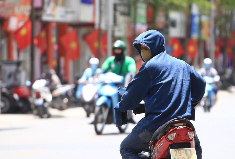 Dưới cái nóng thiêu đốt, người dân tham gia giao thông phải trang bị áo mũ chống nắng kín mít để tránh nắng. (Ảnh: Hoàng Hiếu/TTXVN)