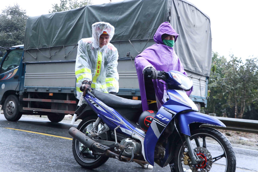 Lực lượng Cảnh sát giao thông giúp người dân di chuyển qua đoạn đường đóng băng trên đèo Ô Quy Hồ. (Ảnh: Nguyễn Oanh/TTXVN)