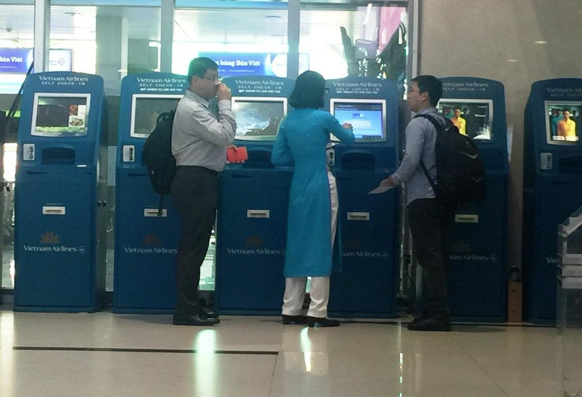 Nhân viên Vietnam Airlines hướng dẫn khách làm thủ tục trực tuyến tại kiosk check-in. (Ảnh: Việt Hùng/Vietnam+)