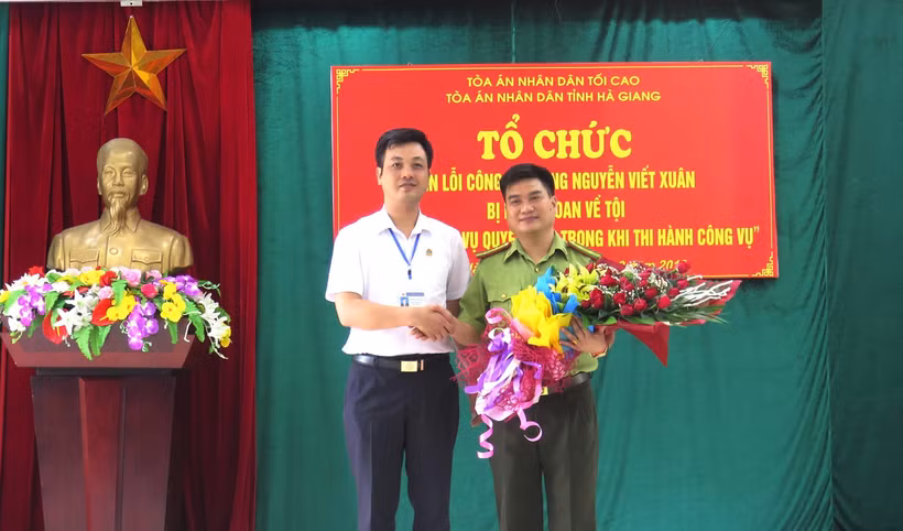 Phó Chánh án TAND tỉnh Hà Giang Trương Huy Huân tặng hoa cho ông Nguyễn Viết Xuân. (Ảnh: Minh Tâm-TTXVN)