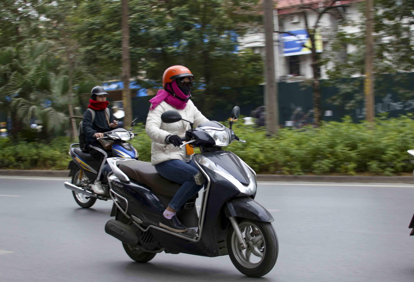 Người dân khi ra đường nên mặc ấm, đeo khẩu trang và mang theo áo mưa đề phòng những cơn mưa. (Ảnh: Tuấn Đức/TTXVN)