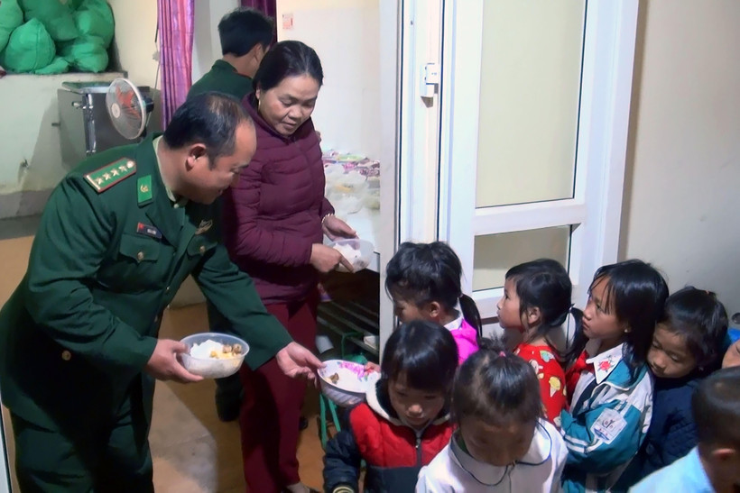 Cán bộ Đồn Biên phòng cửa khẩu Lóng Sập cùng giáo viên chia cơm cho học sinh. (Ảnh: Hữu Quyết/TTXVN)