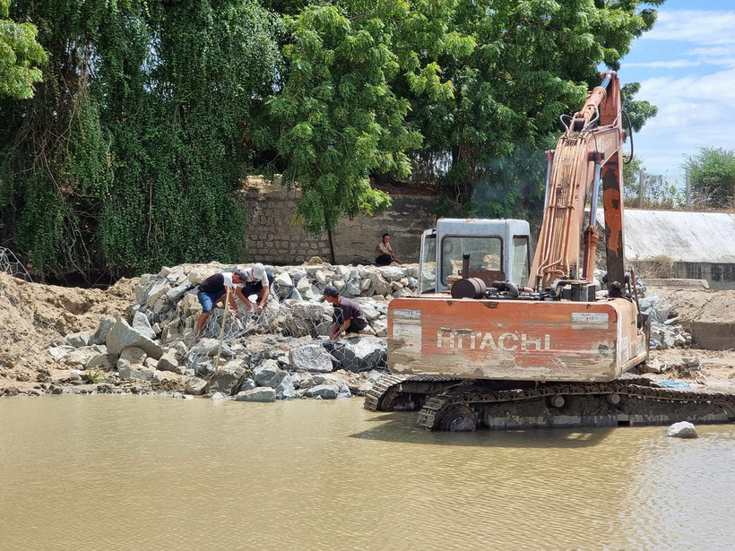 Đơn vị thi công gia cố đập bằng các rọ đá, đắp bao cát để dâng nước. (Ảnh: Nguyễn Thành/TTXVN)