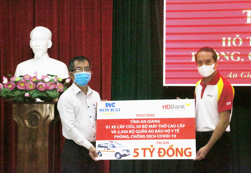 Đại diện Tập đoàn Sovico và Ngân hàng Thương mại Cổ phần Phát triển Thành phố Hồ Chí Minh HDBank (phải) trao bảng tượng trưng tăng tỉnh An Giang 1 xe cấp cứu, 5 máy thở cao cấp, 2.500 bộ quần áo bảo hộ y tế. (Ảnh: Công Mạo/TTXVN)