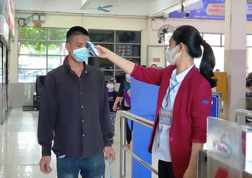 Nhân viên bến xe Giáp Bát kiểm tra thân nhiệt hành khách trước khi ra ôtô để về quê dịp nghỉ 30/4. (Ảnh: Việt Hùng/Vietnam+)