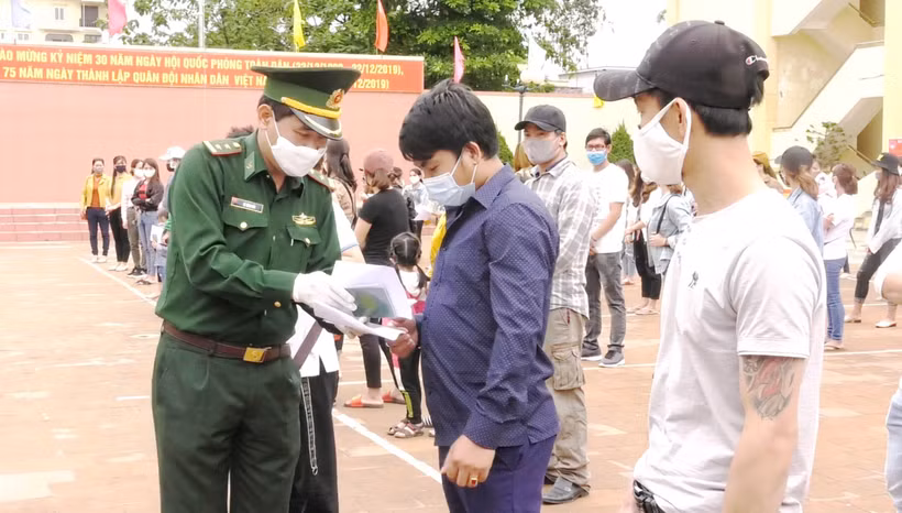Cán bộ biên phòng trao Giấy chứng nhận hoàn thành cách ly phòng chống dịch bệnh COVID-19 cho các công dân. (Ảnh: Võ Dung/TTXVN)