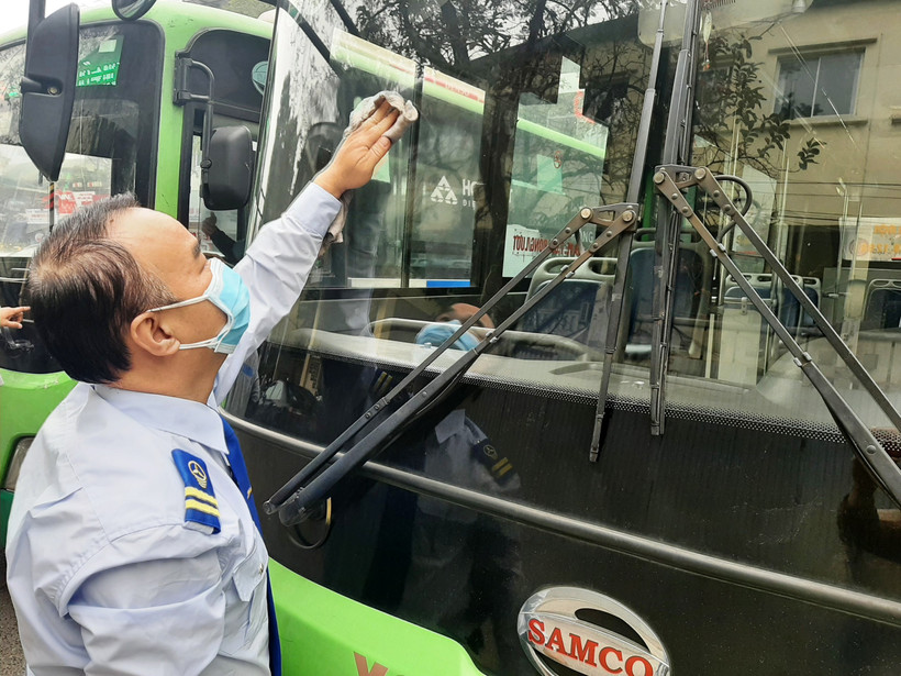 Anh Hồ Xuân Phong, lái xe tuyến số 33 thuộc Xí Nghiệp Tân Đạt đang vệ sinh xe sau hành trình đón khách. (Ảnh: Việt Hùng/Vietnam+)