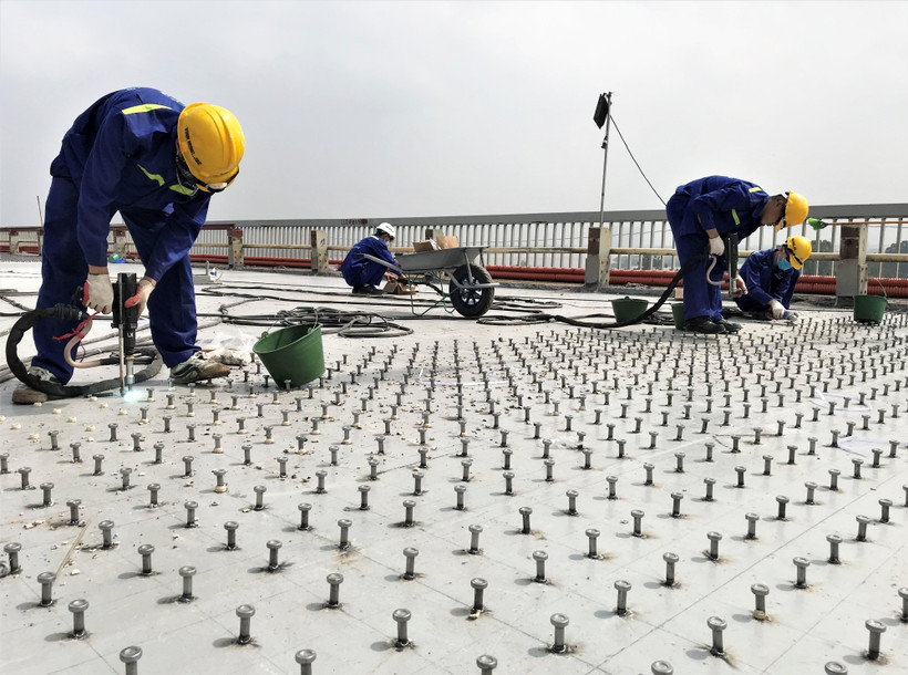 Công nhân tiến hành hàn đinh neo để tạo liên kết giữa bản mặt thép hiện tại và bê tông siêu tính năng UHPC nhằm tăng cường kết cấu chịu lực của mặt cầu Thăng Long. (Ảnh: Việt Hùng/Vietnam+)