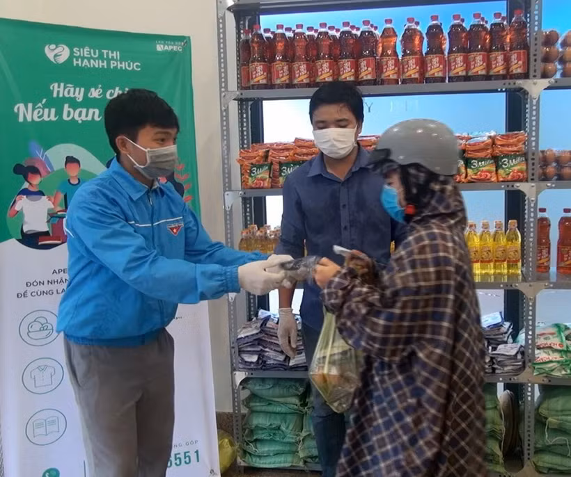 Người nghèo nhận hàng hóa và khẩu trang miễn phí. (Ảnh: Xuân Triệu/TTXVN)