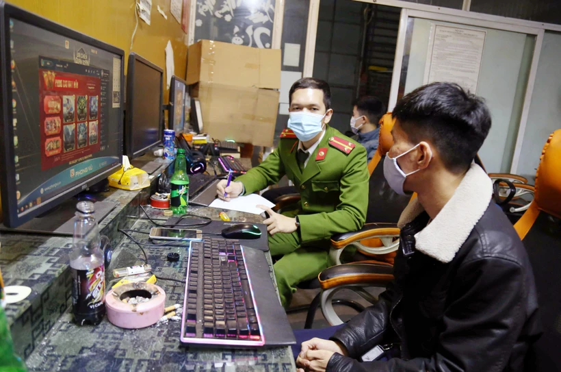 Công an lập biên bản các thanh niên chơi game vi phạm quy định phòng chống dịch COVID-19. (Ảnh: TTXVN phát)