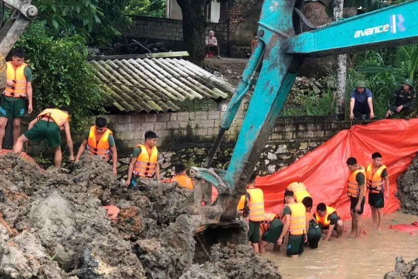 Hơn 100 cán bộ, chiến sỹ Trung đoàn 762 Bộ Chỉ huy Quân sự tỉnh Thanh Hóa dầm mình trong nước lũ nỗ lực khắc phục sự cố. (Ảnh: TTXVN phát)