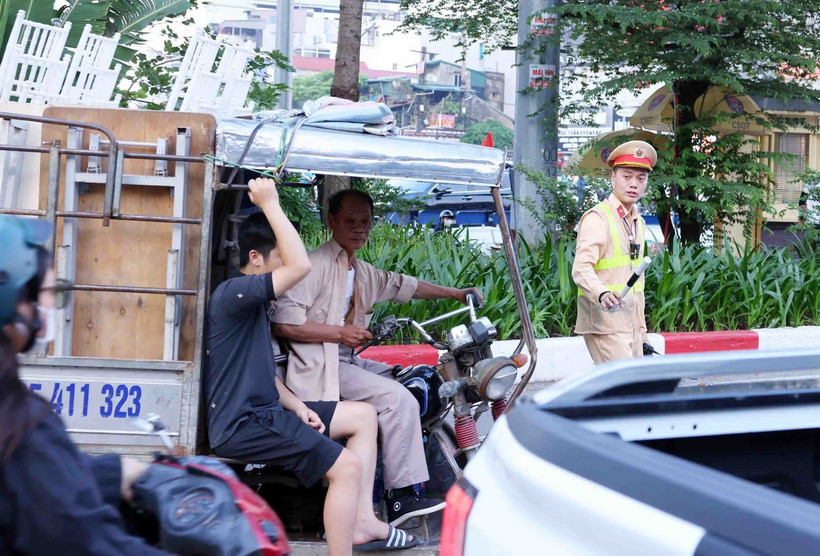 Cảnh sát giao thông dừng xe, kiểm tra và xử lý 1 trường hợp người điều khiển xe ba bánh, bốn bánh tự sản xuất, lắp ráp chở hàng cồng kềnh. (Ảnh: Phạm Kiên/TTXVN)