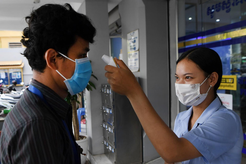Kiểm tra thân nhiệt người dân trước cửa một ngân hàng nhằm phòng dịch COVID-19 lây lan, tại Phnom Penh, Campuchia. (Ảnh: AFP/TTXVN)
