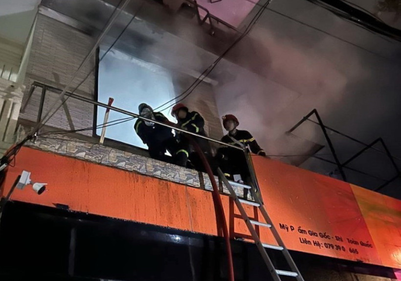 Lực lượng phòng cháy chữa cháy và cứu hộ cứu nạn dùng thang đưa người từ tầng 3 xuống. (Ảnh: TTXVN phát)