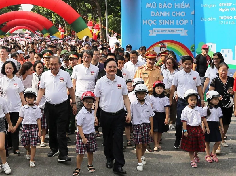 Lãnh đạo Chính phủ và các Bộ, ban ngành đi bộ kêu gọi toàn dân đội mũ bảo hiểm cho trẻ em khi tham giao giao thông. (Ảnh: Việt Hùng/Vietnam+)