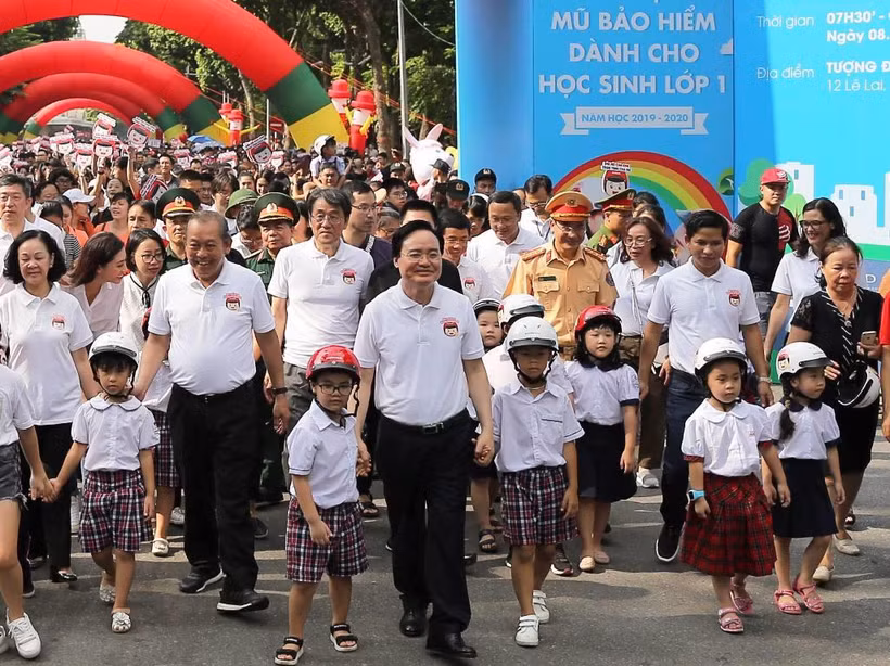 Lãnh đạo Chính phủ và các Bộ, ban ngành đi bộ kêu gọi toàn dân đội mũ bảo hiểm cho trẻ em khi tham giao giao thông. (Ảnh: Việt Hùng/Vietnam+)