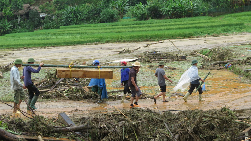 Đưa thi thể được tìm thấy sau cơn lũ dữ ở làng Nủ (Lào Cai) về an táng. (Ảnh: Hồng Ninh/TTXVN)