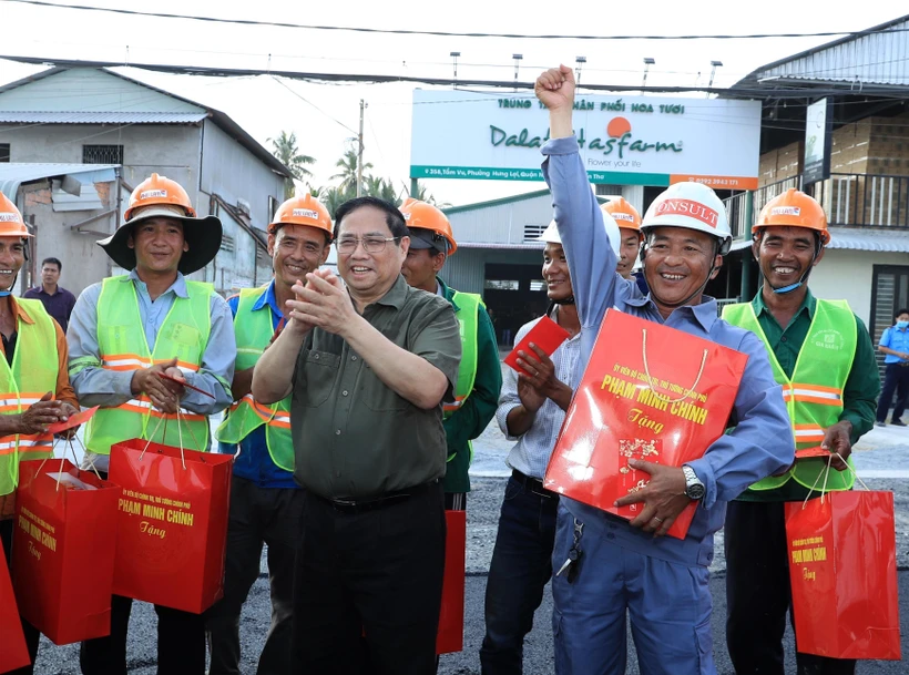 Thủ tướng Phạm Minh Chính tặng quà, động viên công nhân đang thi công tuyến đê kè ứng phó biến đổi khí hậu tại sông Cần Thơ, thuộc Dự án phát triển thành phố Cần Thơ. (Ảnh: Văn Điệp/TTXVN)