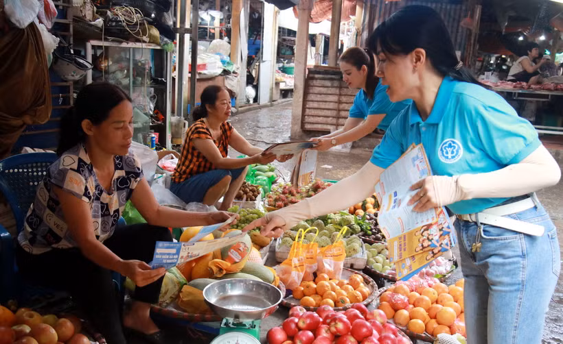 Phát tờ rơi, tuyên truyền chính sách bảo hiểm xã hội cho người dân thành phố Nam Định. (Ảnh: Nguyễn Lành/TTXVN)