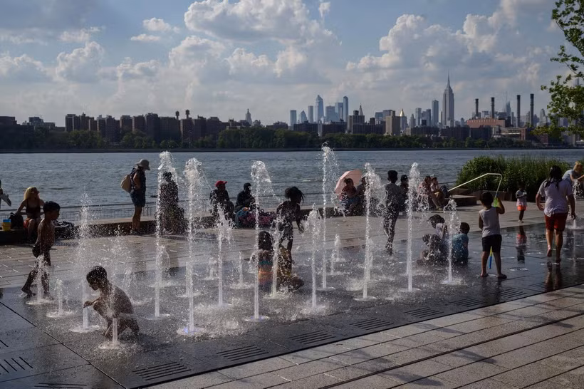 Trẻ em chơi đùa dưới vòi phun nước để tránh nóng tại New York, Mỹ, ngày 30/6/2021. (Ảnh: AFP/TTXVN)