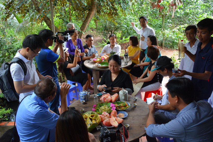 Khách du lịch thưởng thức các món ăn chế biến từ bưởi ở Cồn Hô. (Nguồn: dulichtravinh.com.vn)