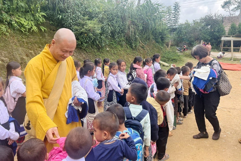 Thượng tọa Thích Minh Quang, Trưởng ban Điều phối và hợp tác Giáo hội Phật giáo Việt Nam tại Lào phát quần áo cho những trẻ em bị ảnh hưởng do lũ lụt ở Lào. (Ảnh: TTXVN phát)