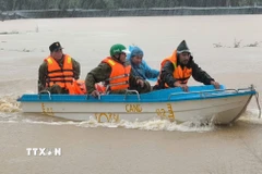 Các lực lượng chức năng sử dụng cano tiếp cận các điểm xung yếu ngập lụt, ứng cứu các hộ dân bị cô lập. (Ảnh: Nguyễn Thành/TTXVN)