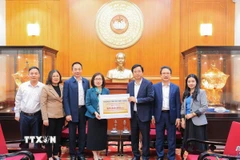 Bà Đoàn Thị Tuyết Nhung, Ủy viên Ban Thường vụ Đảng ủy, Phó Tổng giám đốc TTXVN trao ủng hộ cho đại diện Uỷ ban Trung ương Mặt trận Tổ quốc Việt Nam, ông Cao Xuân Thạo, Uỷ viên Đoàn chủ tịch, Trưởng Ban công tác Xã Hội. (Ảnh: Lê Đông/TTXVN)