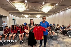 Huấn luyện viên Mai Đức Chung (phải) tặng áo thi đấu có chữ ký của các cầu thủ đội tuyển cho Tổng Lãnh sự Nguyễn Thanh Hà. (Ảnh: Thanh Tú/TTXVN)