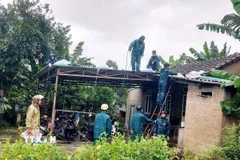 Lực lượng chức năng hỗ trợ, giúp các hộ dân gia cố, chằng chống nhà cửa tránh bão. (Ảnh: TTXVN phát)