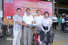 Chủ tịch huyện Naxaithong và Chủ tịch Câu lạc bộ Doanh nghiệp tỉnh Nghệ An tại huyện Naixaithong, thủ đô Viêng Chăn, trao quà cho học sinh nghèo vượt khó. (Ảnh: Xuân Tú/TTXVN)