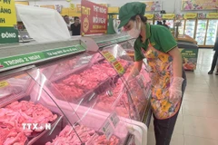 Nhân viên siêu thị thêm hàng vào quầy thực phẩm. (Ảnh: Hương Giang/TTXVN)