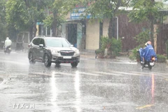 Người dân đi lại trong mưa lớn. (Ảnh: Nguyên Lý/TTXVN)